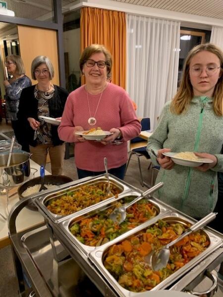 Drei Frauen stehen am Buffet und holen sich Essen